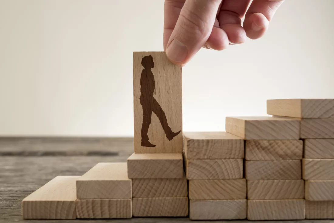 man-holding-with-his-fingers-wooden-domino-with-shape-businessman-walking-up-stairs-climb-up-career-ladder